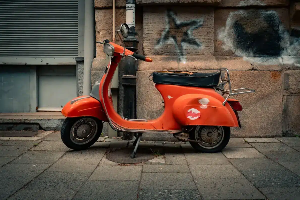 Bunte Mopeds und Roller fahren auf einer Rennstrecke, Fahrer in kreativen Outfits