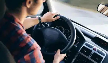 Blick über ein Wohnmobil‑Cockpit mit anonymen Händen am Lenkrad auf die Straße