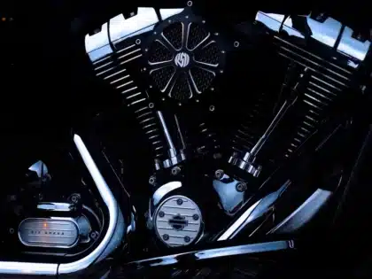 Blick in ein anonymes Motorradmontagewerk mit Rahmen und silhouettenhaften Arbeitern