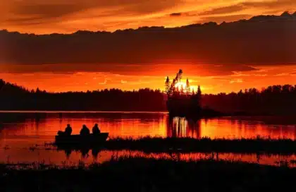 Silhouette eines beladenen Adventure-Motorrads an einer Fährrampe bei Sonnenaufgang