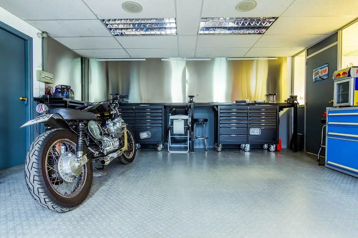 Anonyme Werkstatt mit Offroad‑Motorradrahmen und Technikern bei der Arbeit