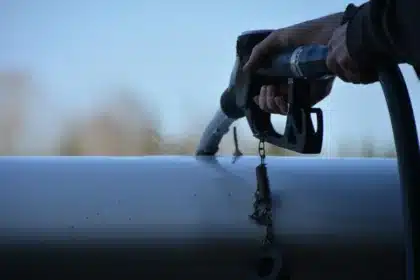Tankstelle mit Zapfpistole und unscharfer Preistafel im Hintergrund