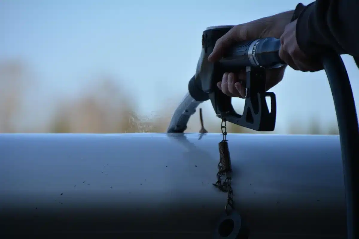 Tankstelle mit Zapfpistole und unscharfer Preistafel im Hintergrund