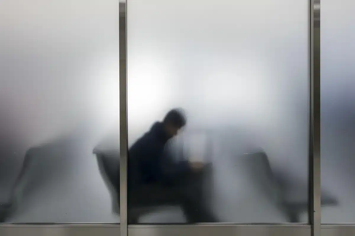 Silhouetten von Reisenden in einem Flughafenterminal vor Sicherheitsabsperrungen